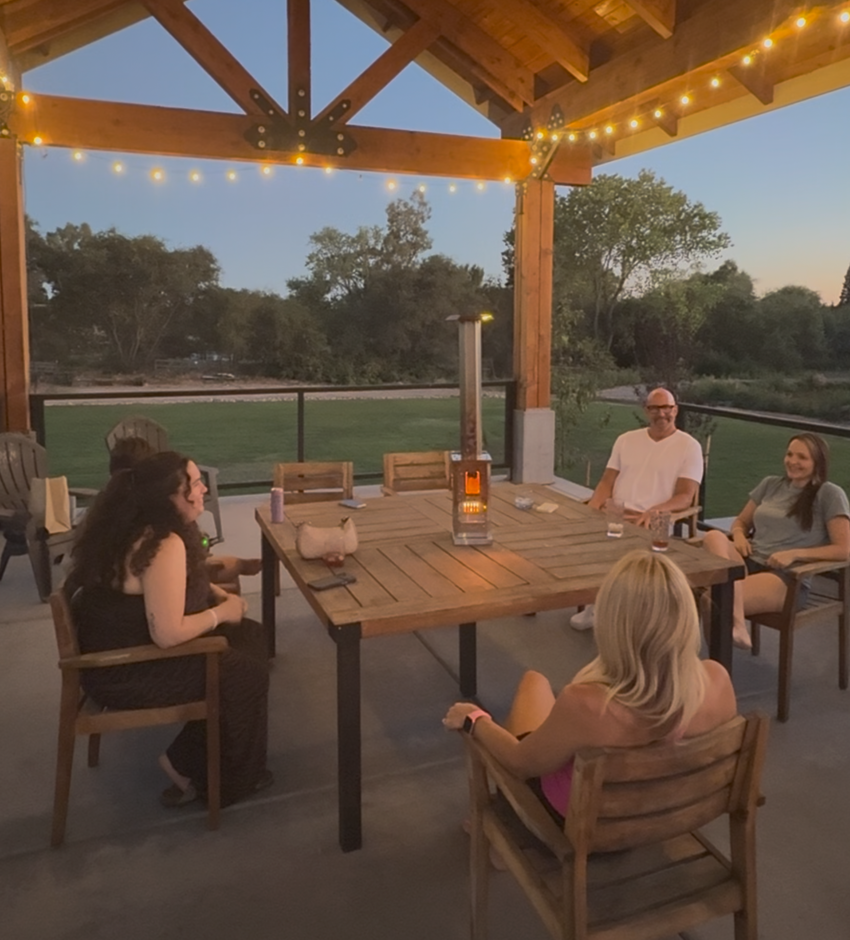 Friends gathered around a table under a pergola with the Sierra Trail™ at dusk