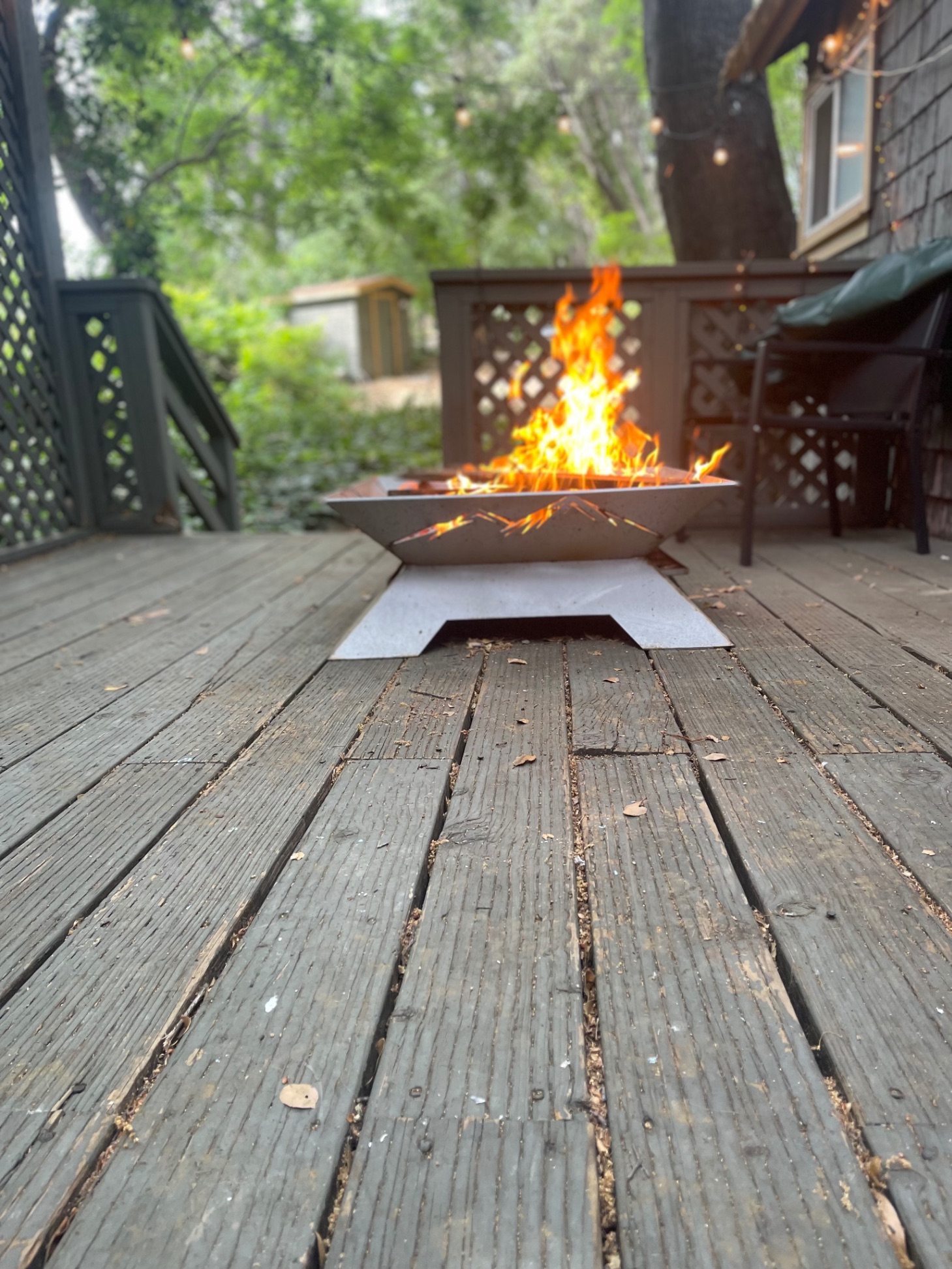 Sierra Ember™ portable stainless steel fire pit burning on backyard deck — wide view